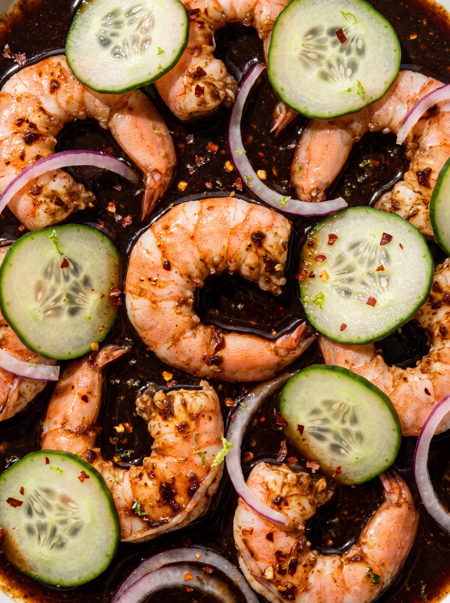 Acercamiento a camarones en salsa de aguachile negro con pepino y cebolla morada