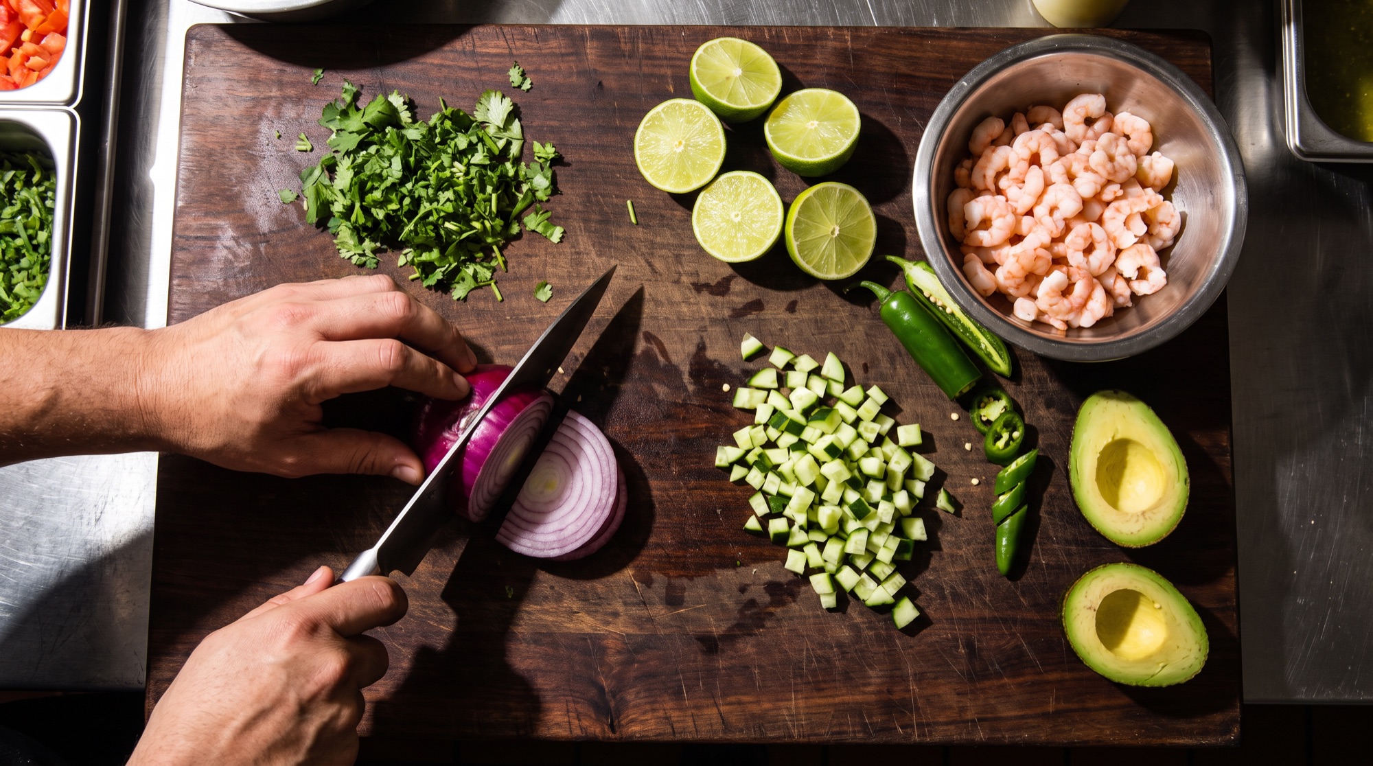 Tabla con cebolla morada, cilantro, pepino, limones, aguacate y camarones